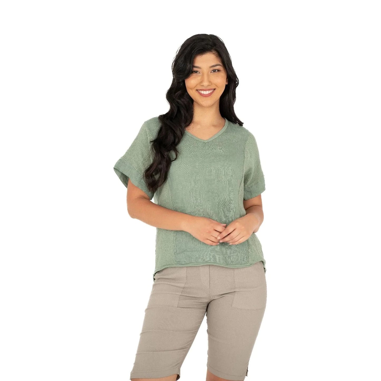 A person smiles while wearing the M Made In Italy V Neck Woven Top in green, paired with beige shorts against a white background.