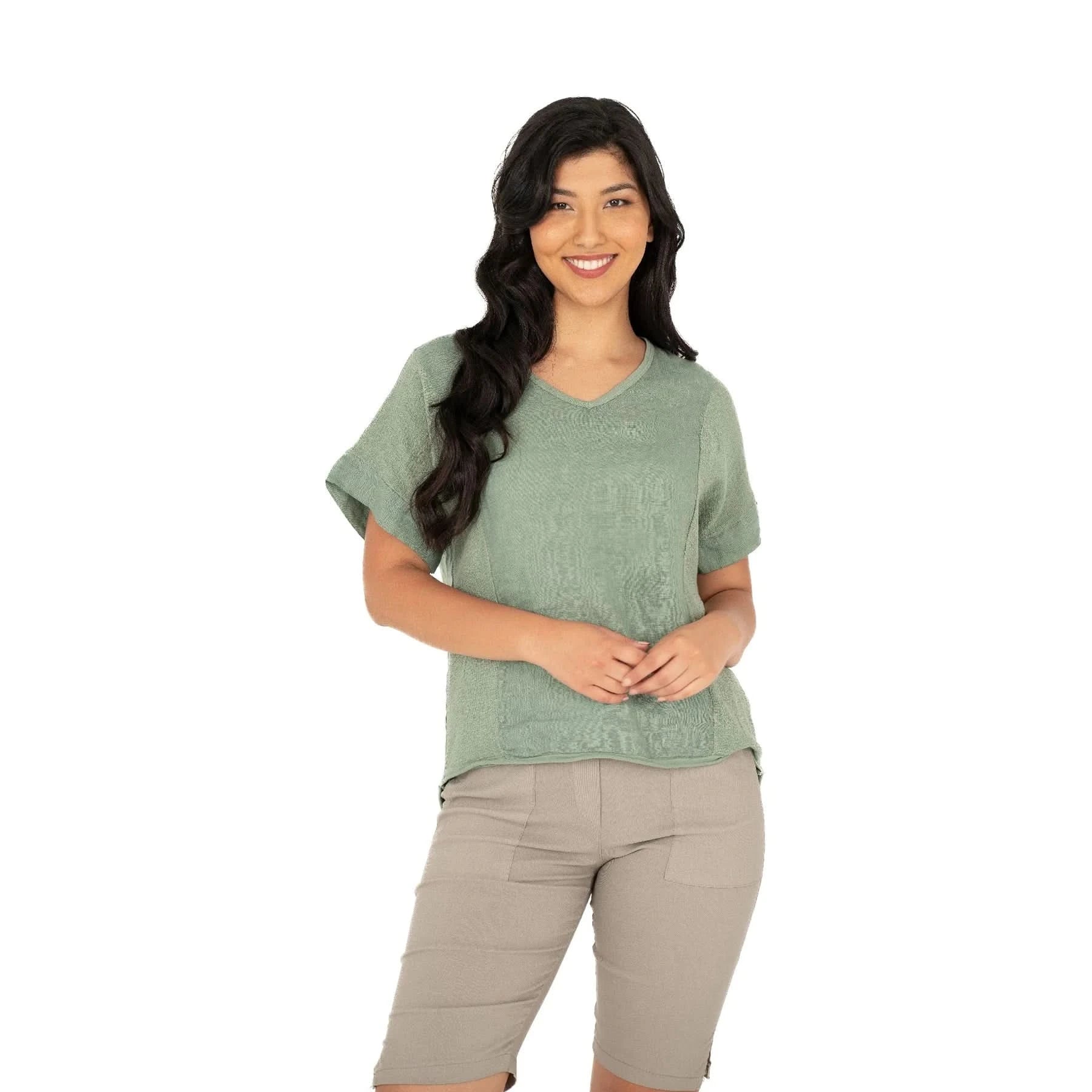 A person smiles while wearing the M Made In Italy V Neck Woven Top in green, paired with beige shorts against a white background.