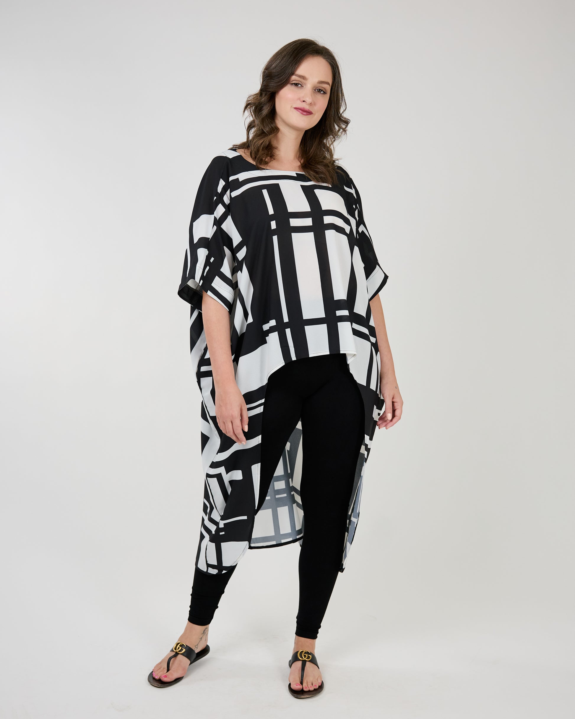 Woman posing in a stylish Shannon Passero Geo Tazia Top with geometric patterns, paired with black leggings and sandals.