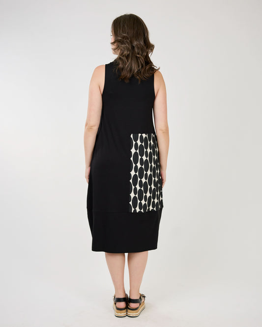 Woman smiling and posing in a unique Shannon Passero Black Patch Sullivan Dress with platform sandals.