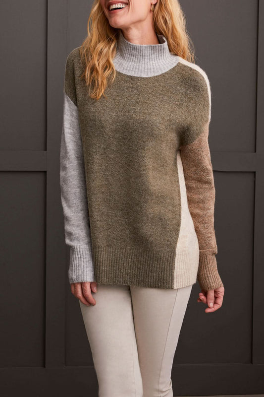 A person wearing the Mock Neck Colorblock Sweater by Tribal, featuring cozy gray, brown, and beige stripes, smiles while holding the collar near their face—truly a fall staple.