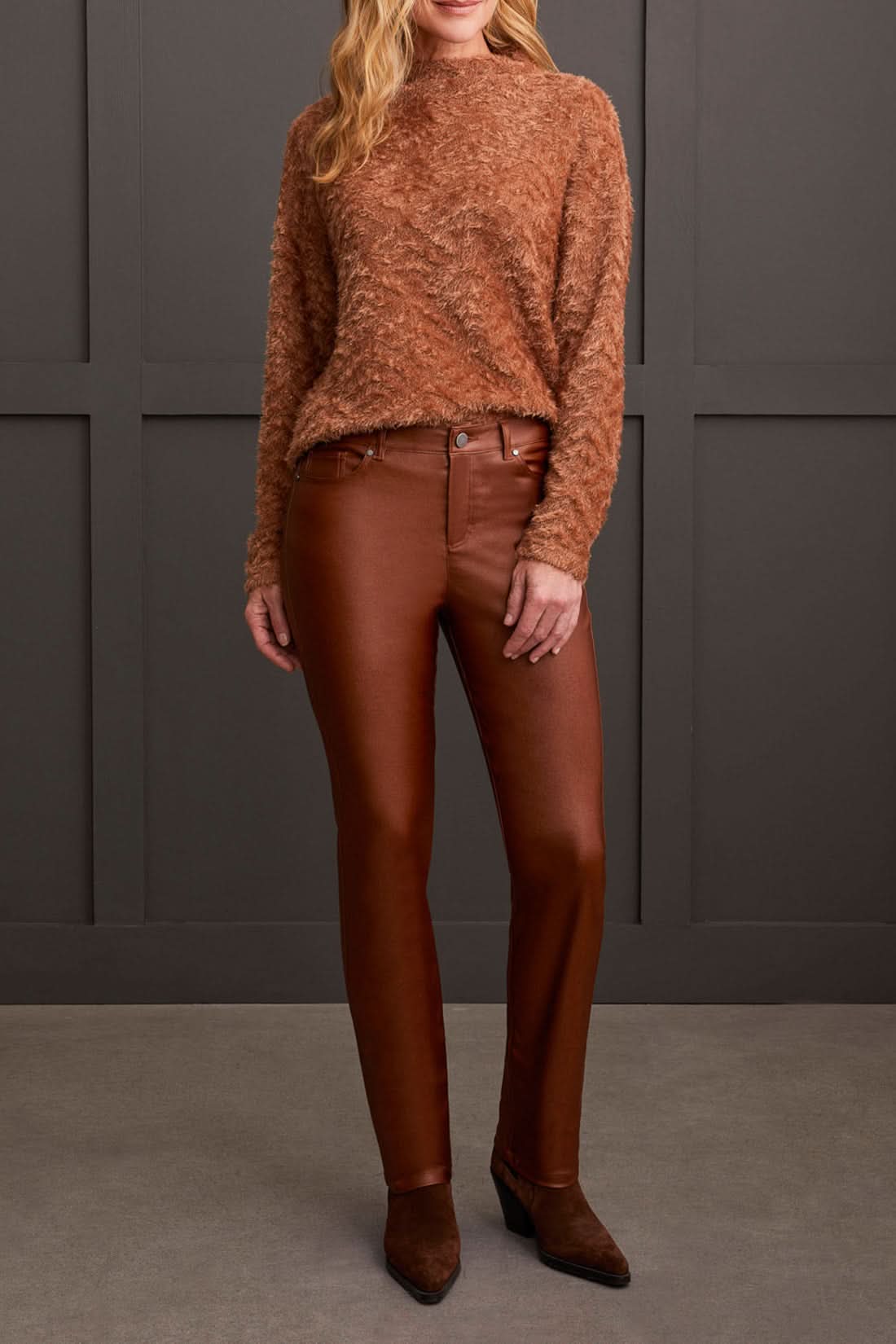 A person stands wearing a textured brown sweater, stylish Tribal Front Fly 5 Pocket Pant, and brown shoes against a gray paneled wall.