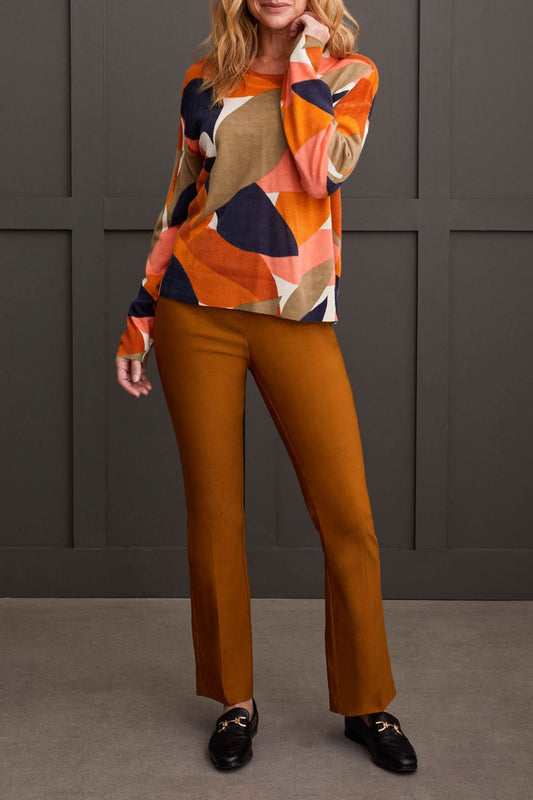 A person wearing a Tribal Long Sleeve Crew Neck Printed Sweater paired with brown pants stands against a dark paneled background.