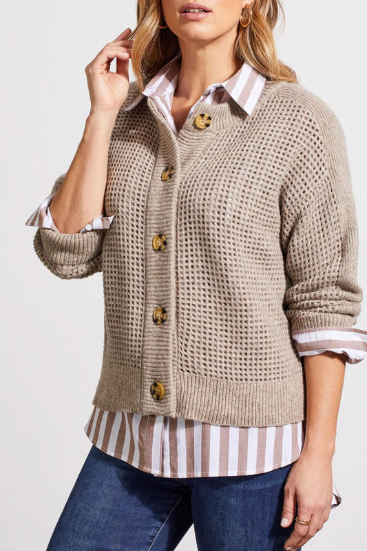 A person wearing a Crew Neck Sweater Cardigan by Tribal in beige, paired with a striped shirt, blue jeans, and brown boots stands against a plain background.