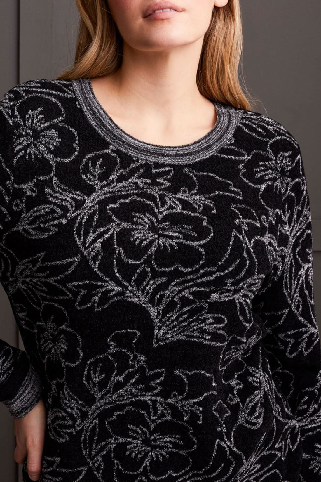 Close-up of a person wearing a cozy, stylish Long Sleeve Scoop Neck Sweater by Tribal, featuring intricate grey floral patterns. The person's head is partially visible, showcasing this perfect piece for fall fashion.