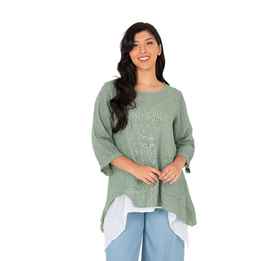 A person with long dark hair stands against a white background wearing the Layered Linen Tunic by M Made In Italy, paired with light blue pants and a white undershirt.