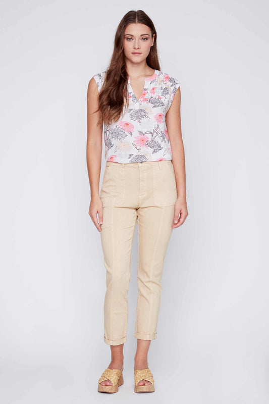 A woman standing against a plain background, wearing a floral print sleeveless top and chic beige CoCo Y Club Front Seam Crop Pants, with her hands slightly behind her.