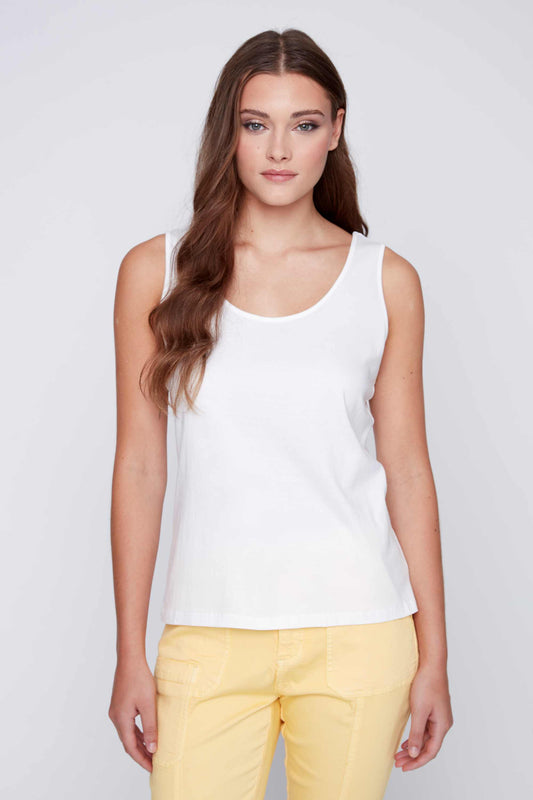 Woman posing in a CoCo Y Club versatile white Round Neck Tank and yellow pants against a grey background.