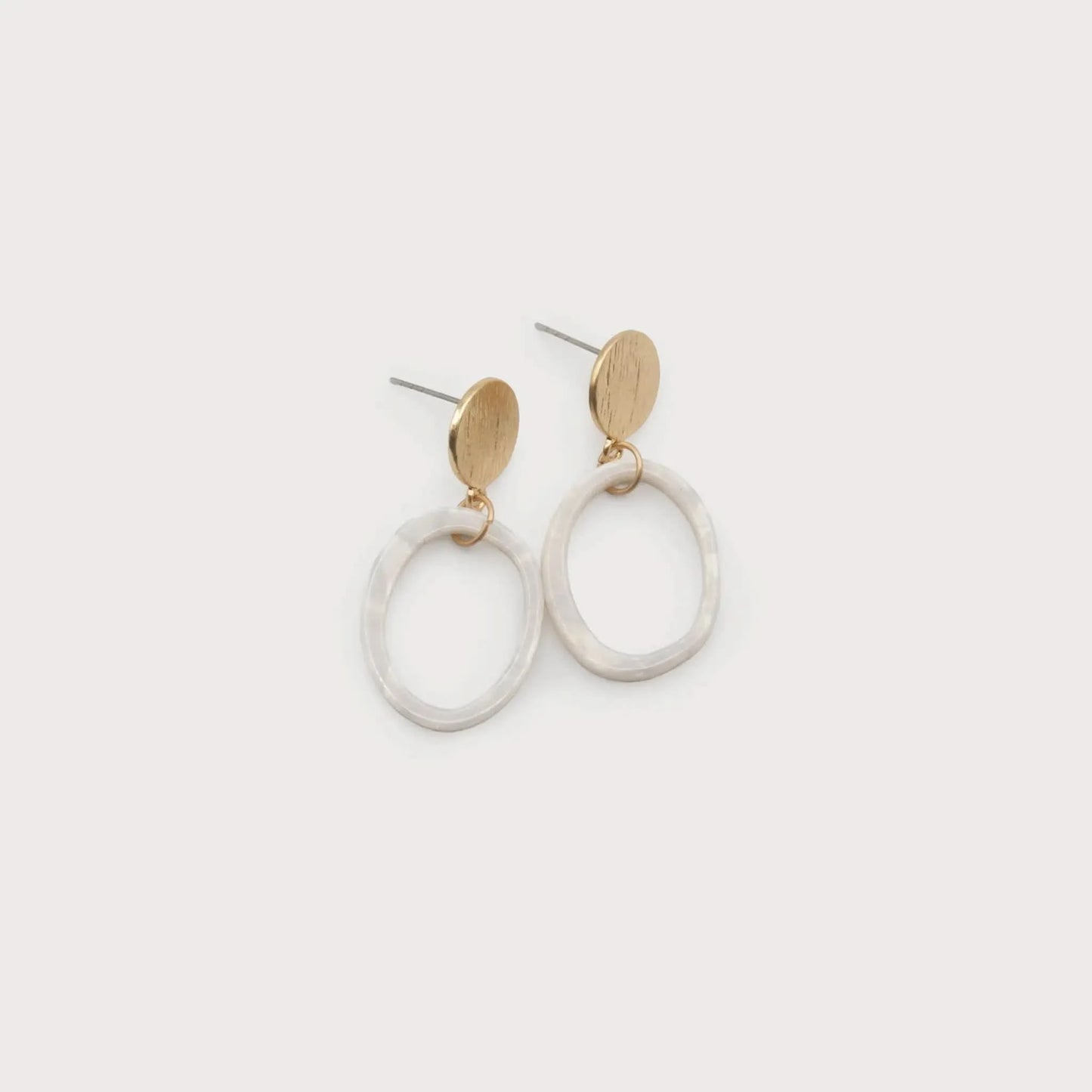 The Caracol Resin Hoop Earrings White feature gold oval studs with round, white, textured resin hoops suspended below, shown against a plain light background.