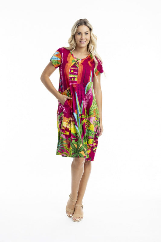 A woman poses against a white background in the Orientique Printed Cotton Short Sleeve Bubble Dress with a vibrant tropical print and beige sandals—ideal for adding playful style to your summer wardrobe.