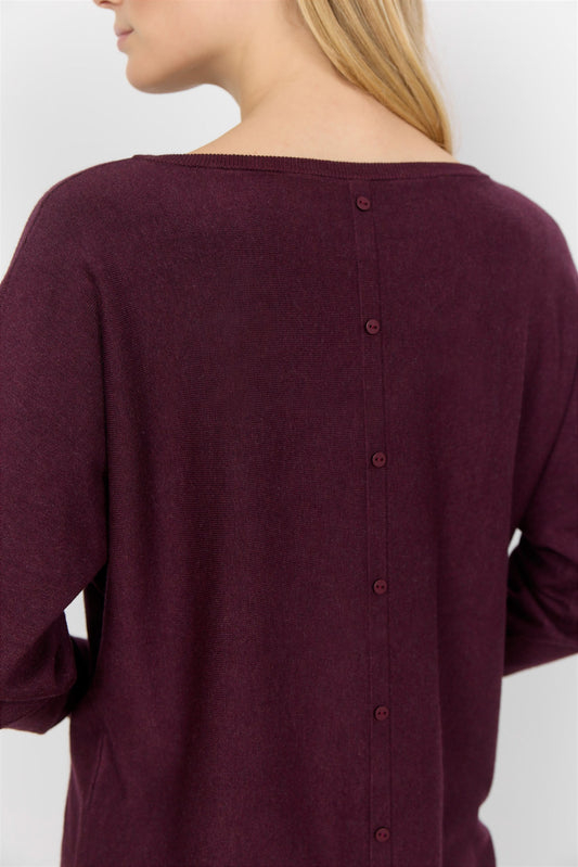 A person with long blond hair is wearing a comfortable Soya Concepts Dollie 620 Long Sleeve Sweater in maroon with button detail, paired with black pants, and is standing against a plain white background.