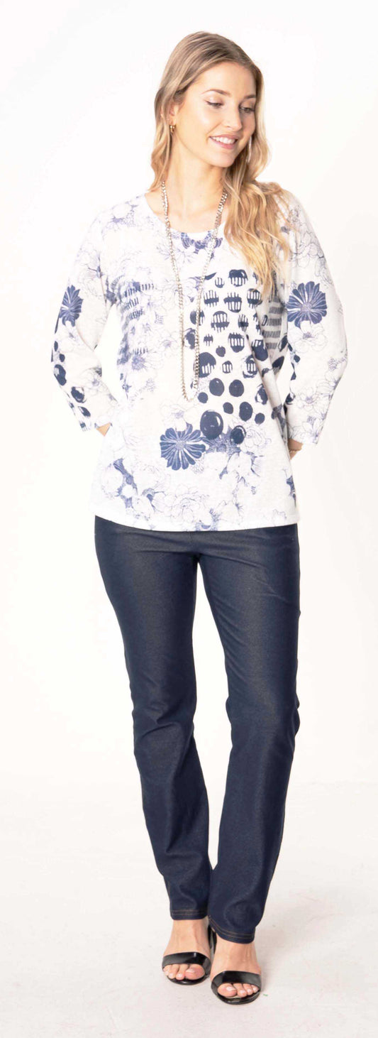 A stylish woman is posing in a Julia Divina blue motif long sleeve top and jeans.