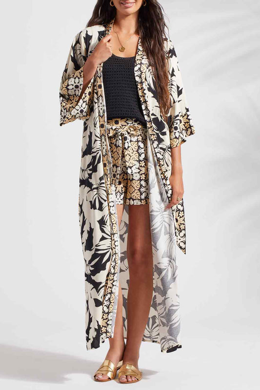 A woman wearing a Tribal 3/4 Sleeve Duster in Wailea kimono and shorts strikes the pose in black and white attire.
