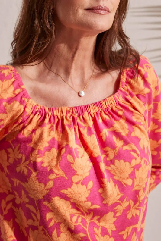 Woman wearing a pink and orange floral dress with a pearl necklace and a Tribal 3/4 Sleeve Peasant Square Neck Top in lightweight fabric.