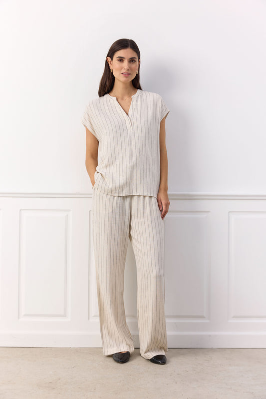 A person wearing a sleeveless gray top, Soya Concepts PAULA 2B Cream Pant, and black shoes stands against a white background.