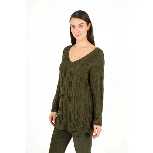 Dressed in an M Made In Italy Cable Knit Oversized V Neck Sweater paired with pants, a person stands with their arms crossed and a subtle smile against a plain white backdrop.