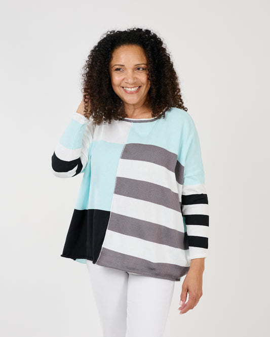 Woman smiling at the camera while playfully gesturing with her hand on her shoulder, wearing a Shannon Passero Lyara Longsleeve Crew Neck Top.