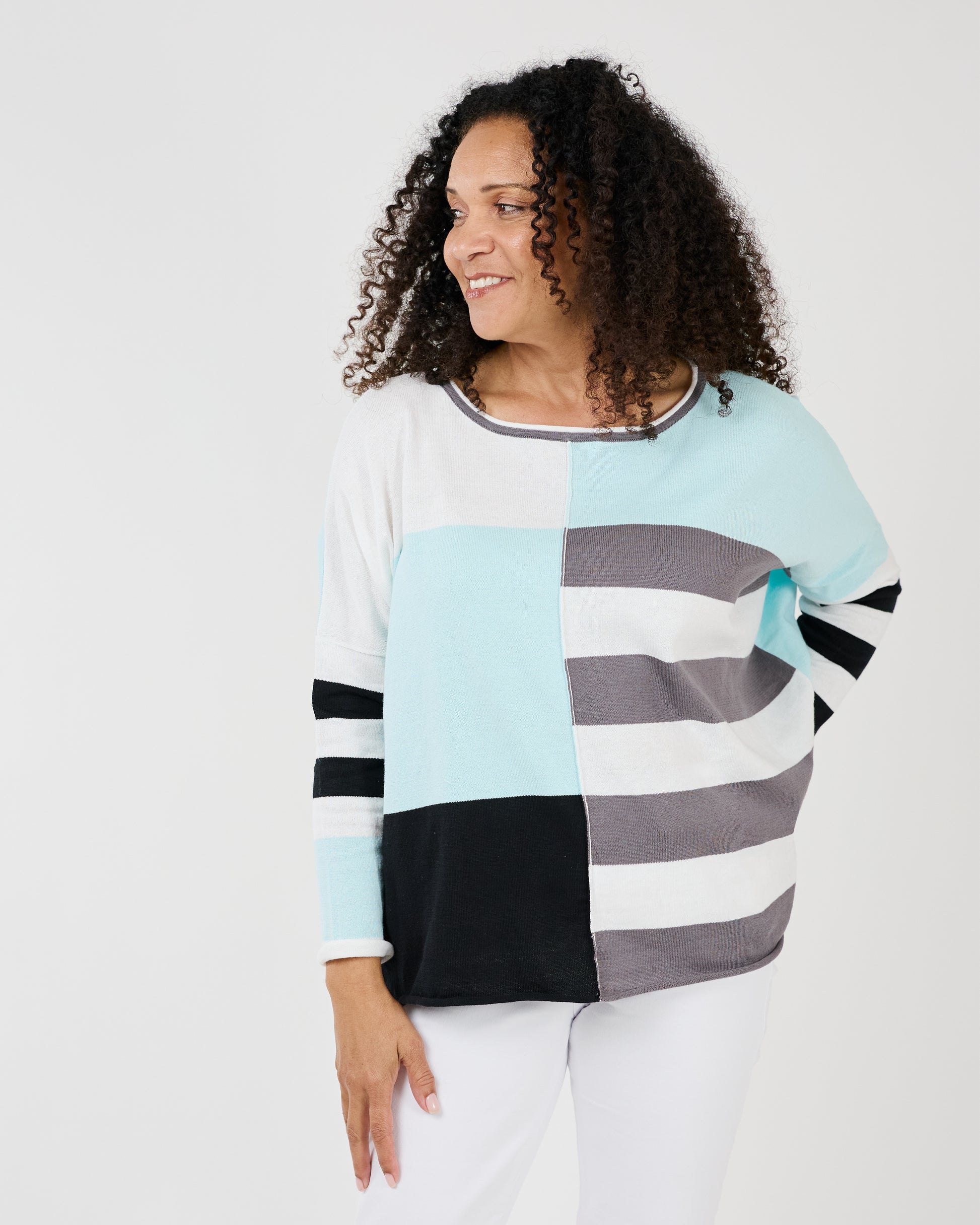 Woman smiling at the camera while playfully gesturing with her hand on her shoulder, wearing a Shannon Passero Lyara Longsleeve Crew Neck Top.