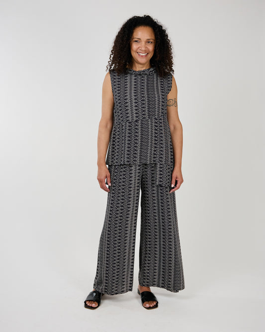 Woman in stylish Shannon Passero Veronica Top and wide-leg pants smiling and standing against a neutral background, enjoying the comfortable fit.