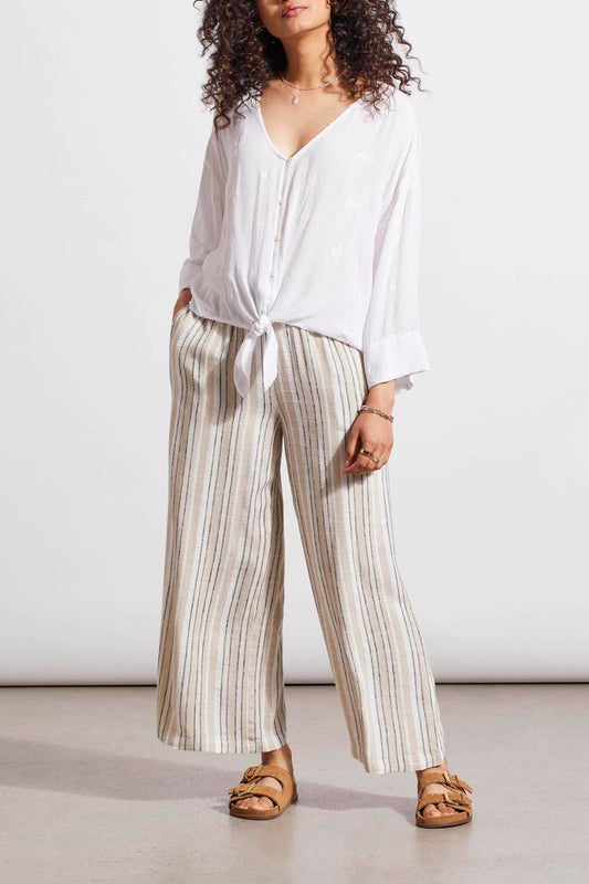 Woman in a Tribal Button Front Kimono Blouse in White and striped trousers standing against a plain background.