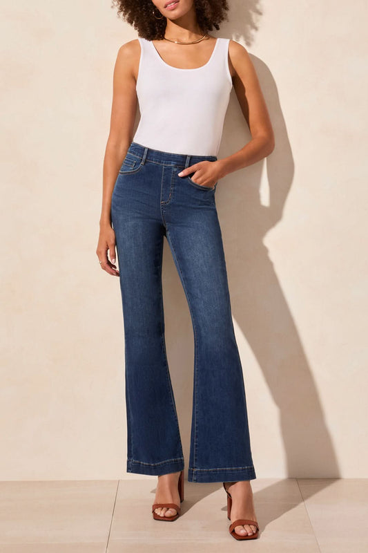 Wearing a white sleeveless top, the person stands against a light background in Tribal's AUDREY PULL-ON FLARE JEANS POCKETS.
