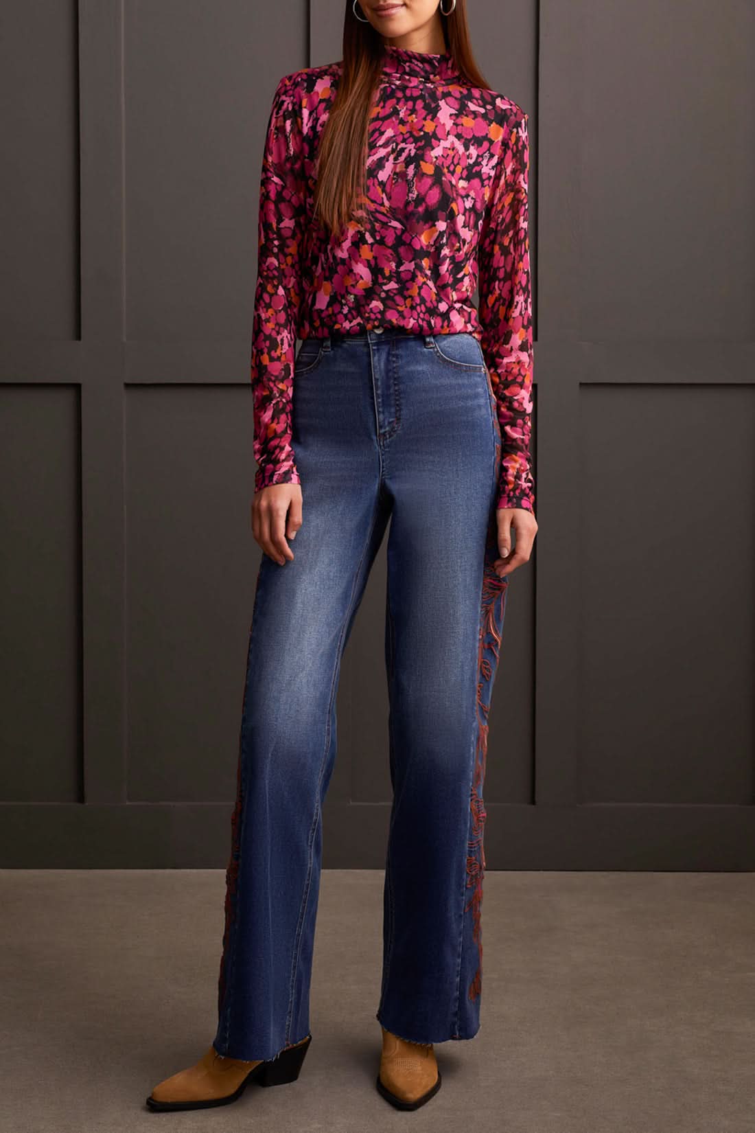A person wearing a cozy Tribal Turtleneck Lined Top and high-waisted wide-leg jeans stands in front of a paneled wall. Brown shoes are visible at the bottom of the jeans, completing this perfect winter wardrobe look.
