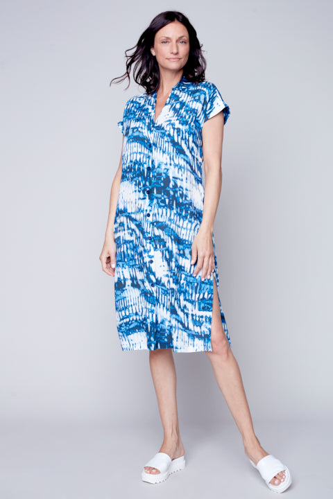 A woman in a chic, blue and white patterned Carre Noir short sleeve woven dress standing against a grey background.