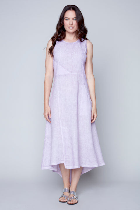 Woman standing in a studio wearing a sleeveless lilac Carre Noir Linen Knitted Dress with Pockets and sandals.
