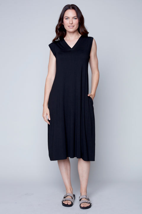 Woman in a black Carre Noir V Neck Knitted dress standing against a gray backdrop.
