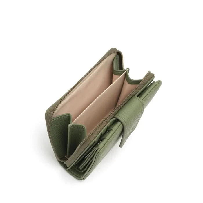 A person in a light gray shirt and beige pants holds The Lucie Small Wallet by Co-Lab, an eco-friendly, compact green wallet with both zipper and snap closures.