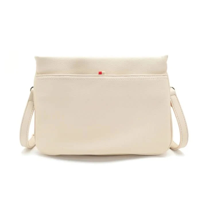 A person wearing a light gray blouse and beige pants carries Co-Lab’s The Nina Crossbody, an eco-friendly light green recycled vegan leather bag.