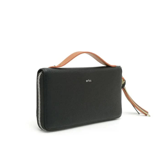 A woman in a light gray button-up shirt and beige pants holds Co-Lab’s sustainable 'ALEXX' Wallet in light green near her chest.