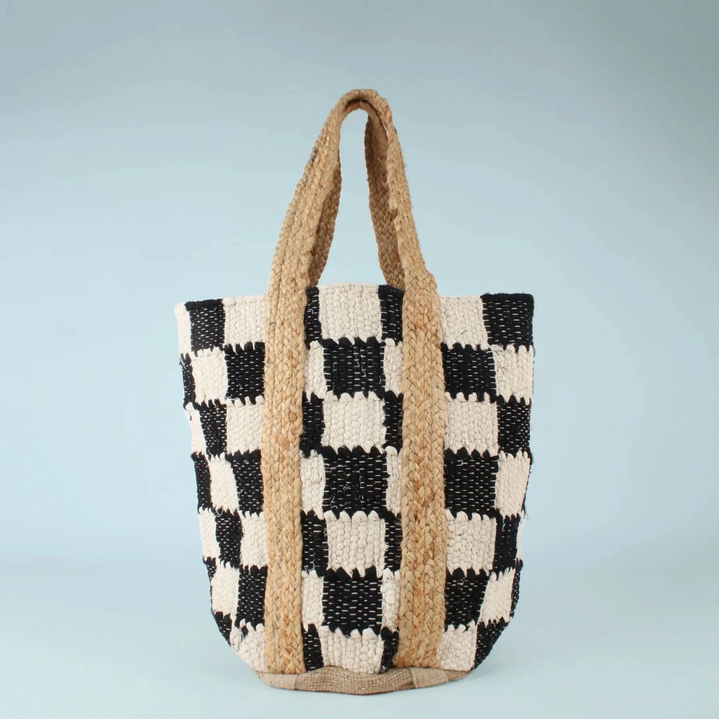 The Co-Lab Laguna Beach Tote Bag showcases a chic black-and-white checkerboard pattern and a sturdy woven jute handle, standing upright against a plain background.