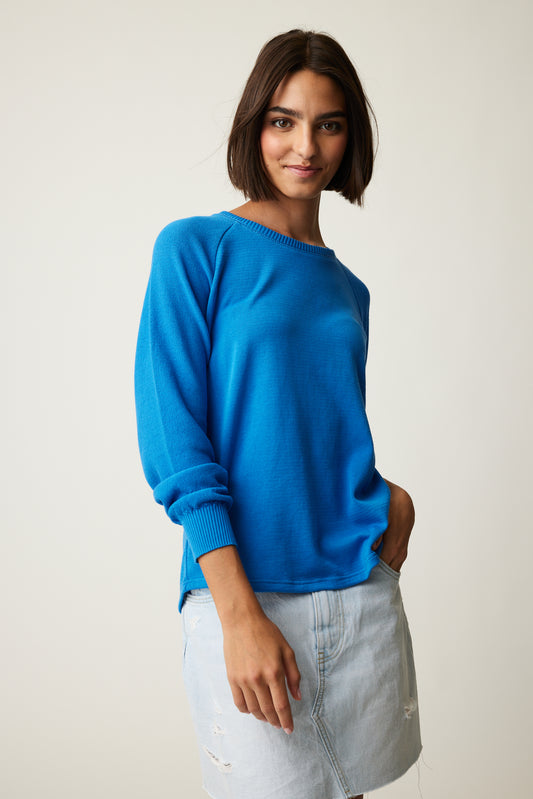 A model wearing a cozy blue Parkhurst Joslyn Sweatshirt and denim skirt.