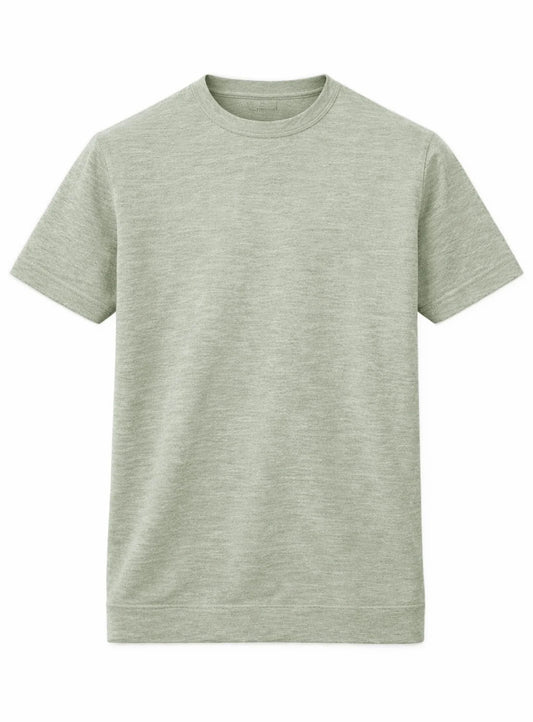 A man showcases effortless summer style in a Point Zero Mens Short Sleeve Active Top, paired with gray pants and white sneakers, standing against a plain background with one hand in his pocket.