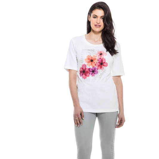 Woman wearing a fashionable Orly Petal Pink Tee with floral print paired with light gray pants.