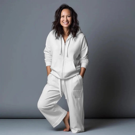 A woman smiling in a white Point Zero Essential Hoodie, made from high-quality materials, against a grey background.