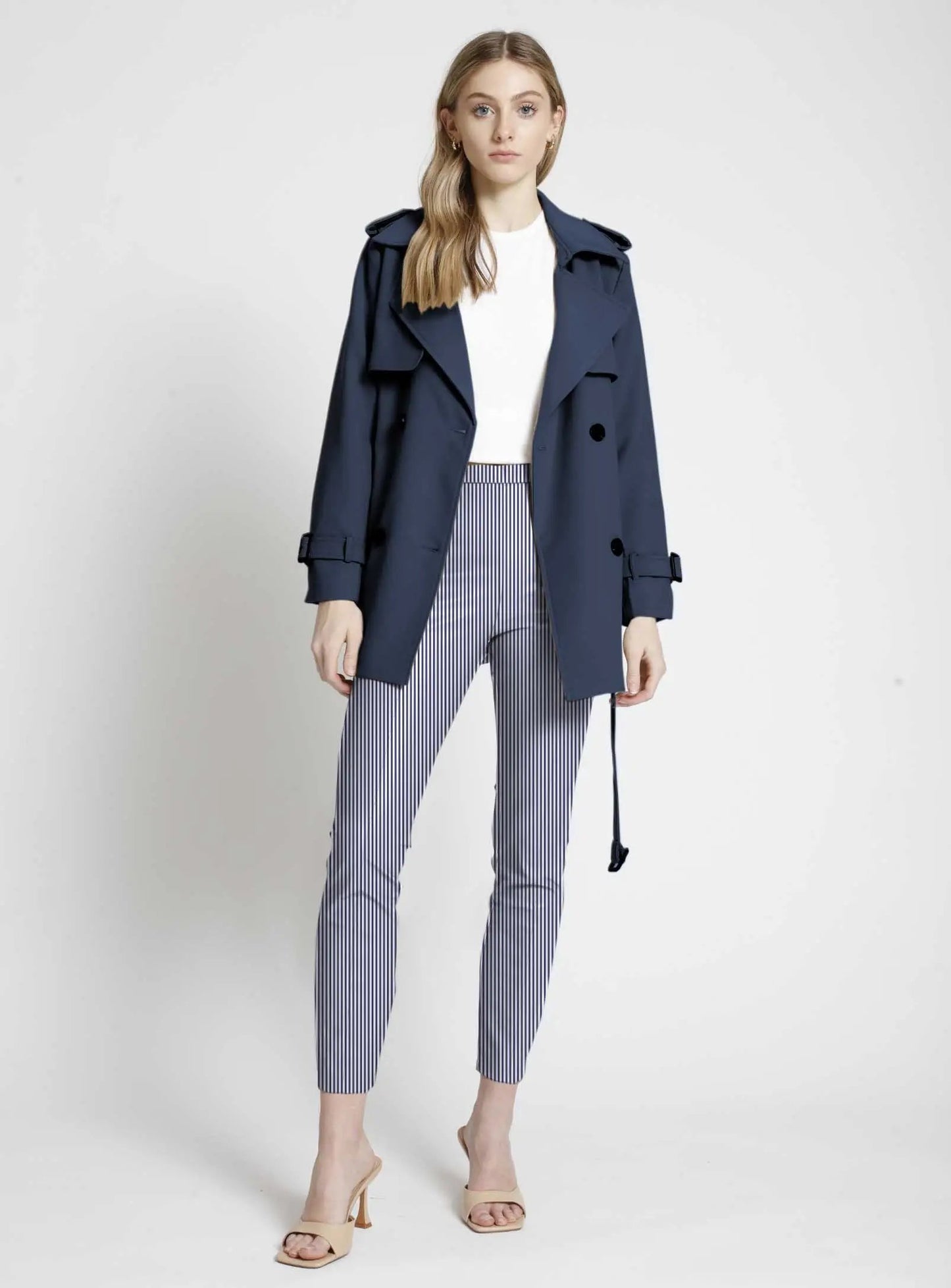 Woman modeling a navy trench coat with comfort-style Point Zero Pull-on Stripe Crop Pants and open-toe heels against a neutral background.