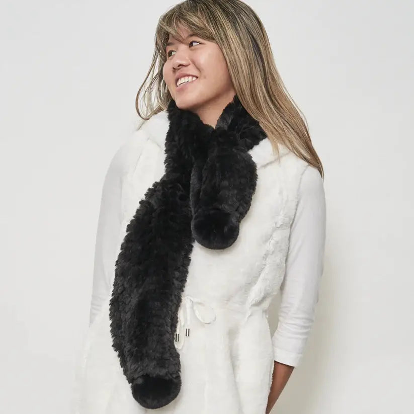 A woman wearing a Bunny Hop Pom Scarf from Furious Fur.