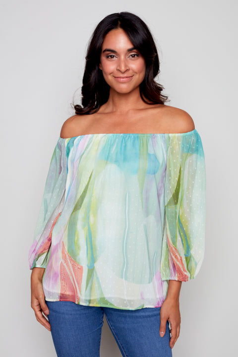 A woman in a Claire Desjardins Off The Shoulder Flowy Blouse looks stylish and comfortable.