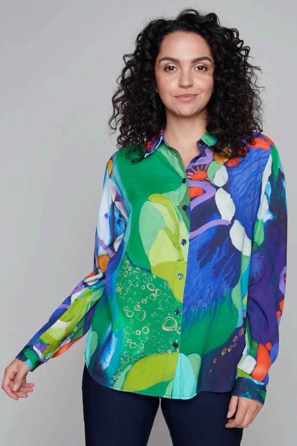 A style-conscious person wears the Button Up Floral Abstract Shirt by Claire Desjardins, striking a pose against a muted gray backdrop.