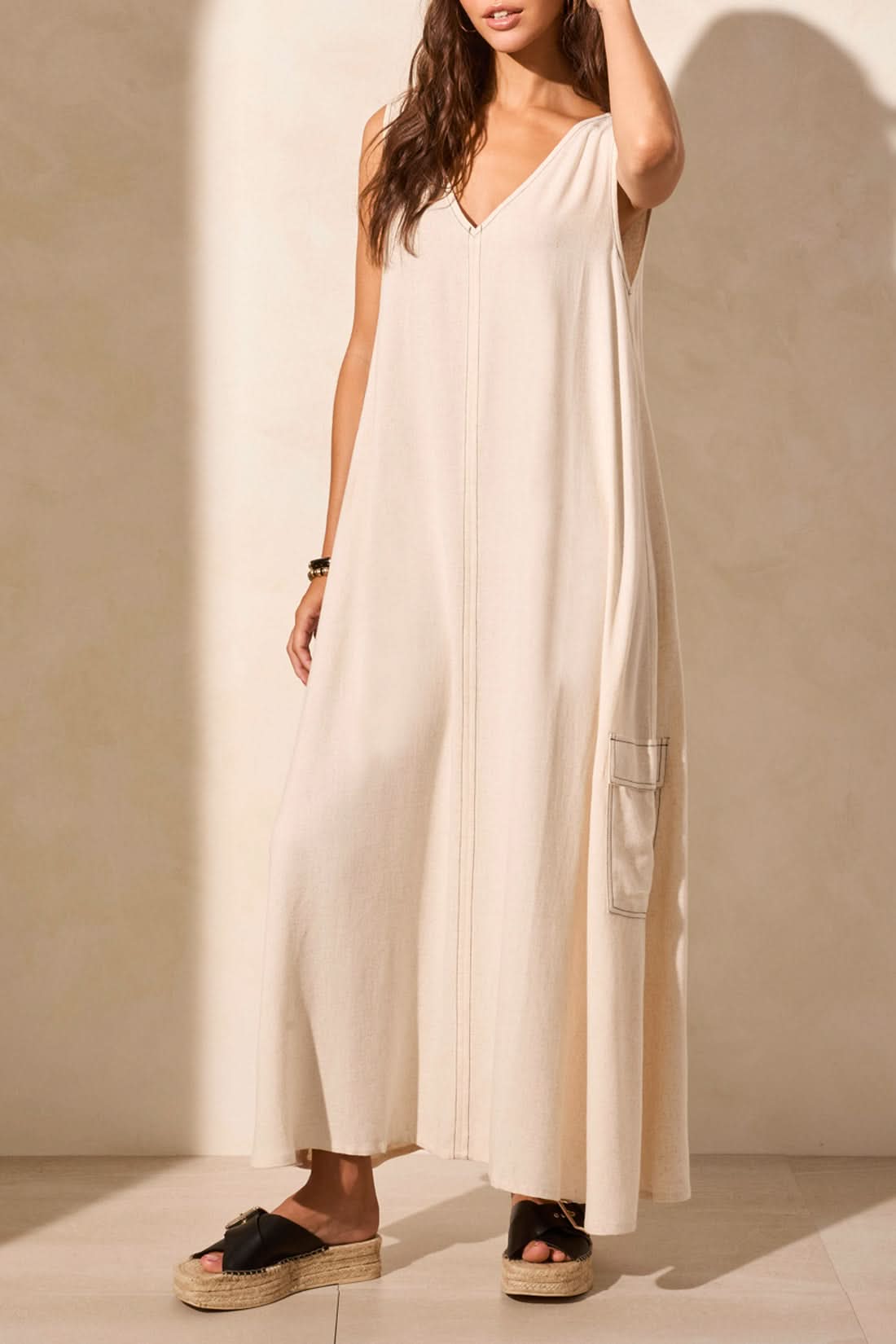 A woman stands against a plain backdrop in Tribal's Sleeveless V-Neck Cargo Dress, exuding effortless fashion. Her right hand rests at her side as the minimalist elegance is captured with her left arm out of frame.