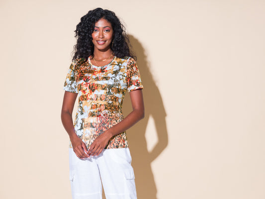 A woman wearing an Alison Sheri Round Neck Leopard Print Tee and white pants.