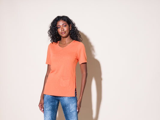 A woman wearing a stylish orange Alison Sheri Short Sleeve Classic Tee with Front Pocket.