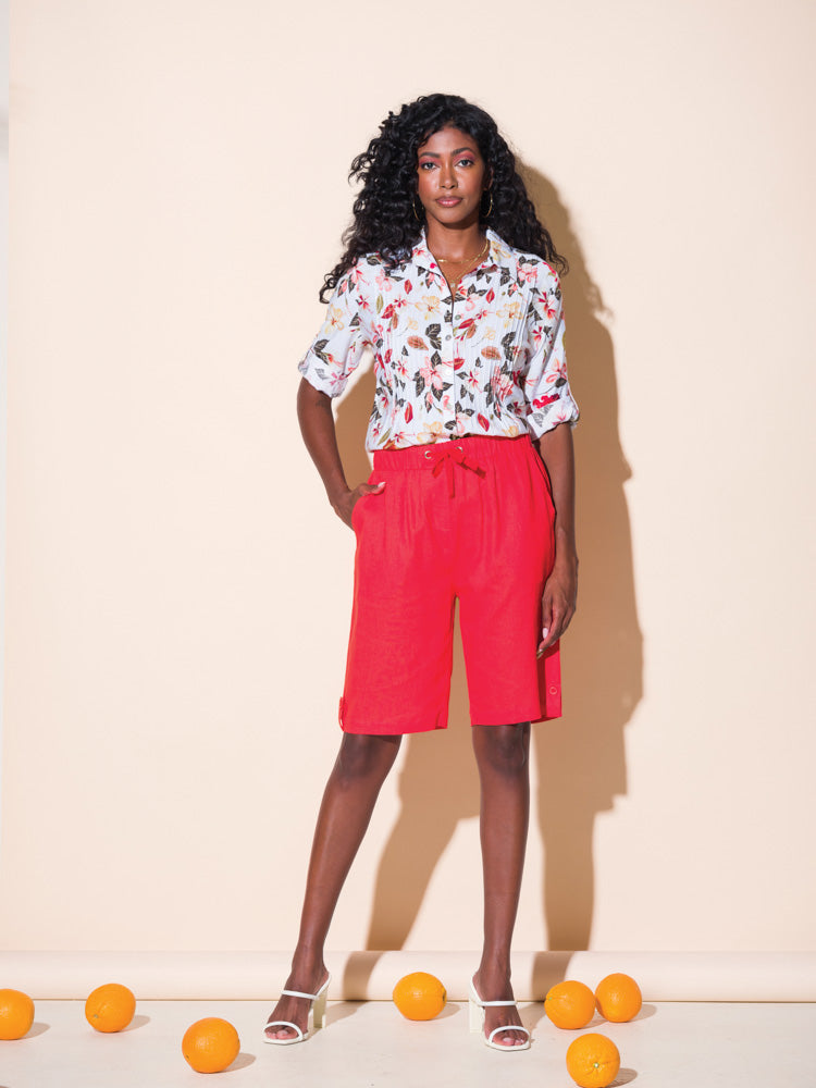 A woman in Alison Sheri Bermuda Shorts with Front Tie posing in front of oranges.