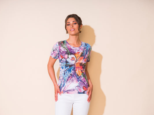 A woman wearing an Alison Sheri Round Neck Multi Floral Tee and white pants.