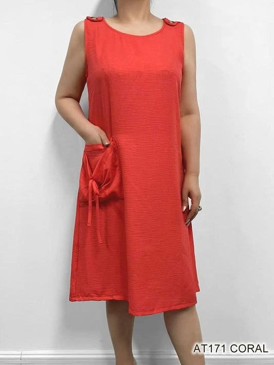 Woman modeling a One Pocket Coral Dress from Fashion Cage in her wardrobe with side pocket detail.
