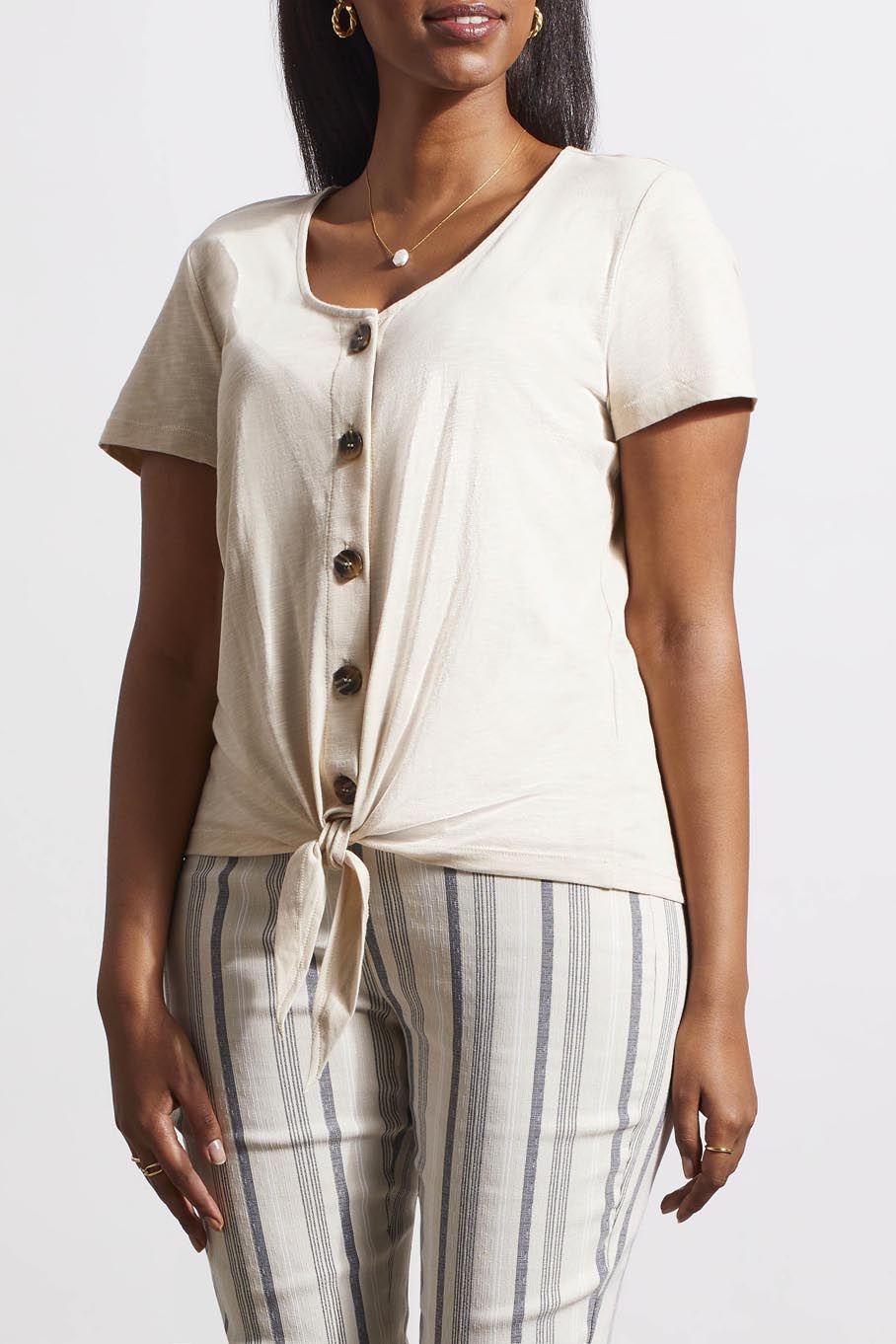 Woman in a versatile style, beige Tribal Button Knot Hem Top and striped trousers.