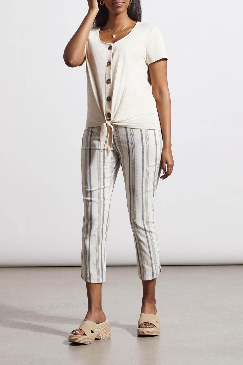 Woman in a versatile style, beige Tribal Button Knot Hem Top and striped trousers.
