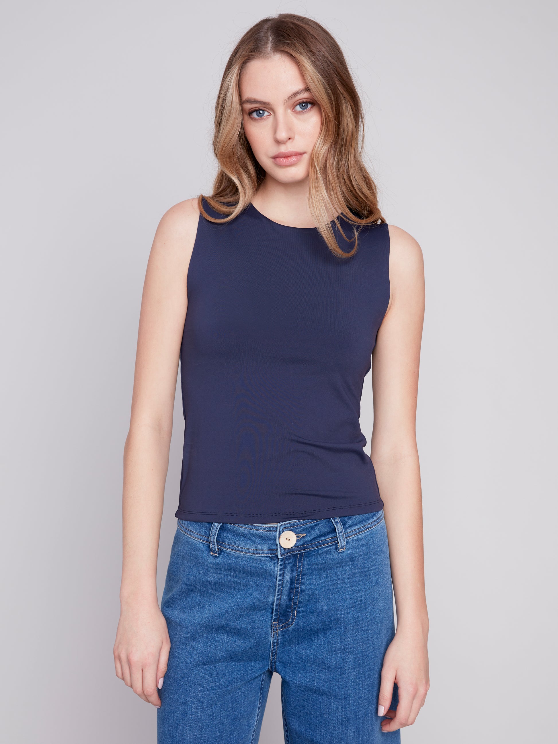 The fashionable model is wearing a comfortable Charlie B navy Sleeveless Rib Tank Top and blue jeans.